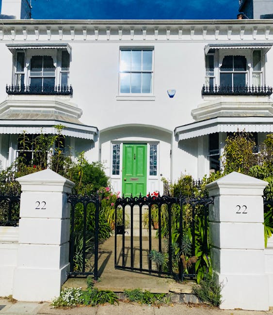 A picturesque garden scene in front of a classic black door with four panels, accessed via a stone staircase with weathered, textured steps. Surrounding the entrance, there is a lush, flowering camell